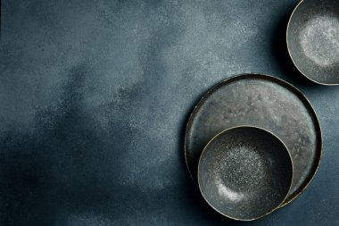 Koyu renk seramik kaplar ve tabaklar. Gri beton arkaplanı kapatın. Metin için boş alan.