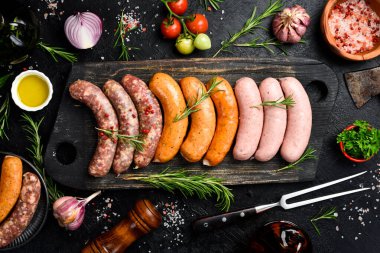 Büyük boy barbekü sosisi: sığır eti, domuz eti ve tavuk sosisi. Tahta kesme tahtasının üzerinde. Üst görünüm.