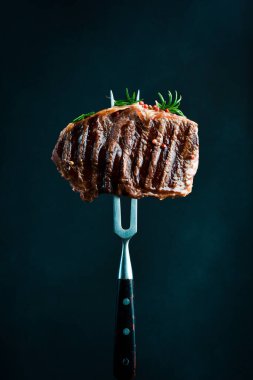 Biberiyeli biftek ve çatallı baharat. Izgara biftek. Siyah bir arkaplanda.