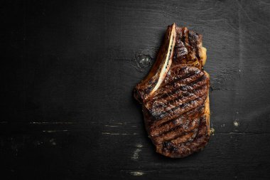 Kemik üzerinde biftek. Tomahawk biftek siyah ahşap arka planda. Üst görünüm. Ücretsiz kopya alanı.