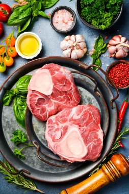 Tavada çiğ Ossobuco bifteği. Gri bir taş masada Ossobuco dana bifteği, baharat, ot, tereyağı ve tuz pişirmek..