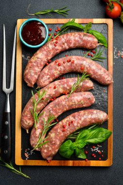 Biberiye ve baharatlı çiğ sığır eti sosisi ızgaraya hazır. Tahta kesme tahtasının üzerinde. Kapat..