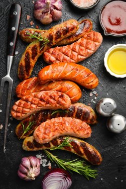 Izgara sosis ve siyah taştan arka planda metal barbekü çatalı. Üst görünüm, tasarım veya metin için boş alan.