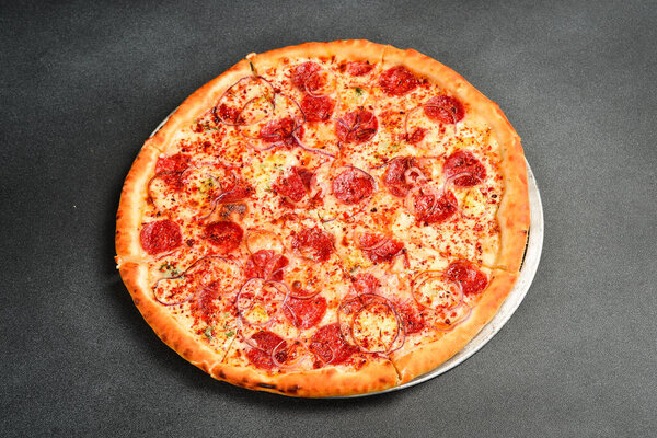Итальянская пицца с салями с пепперони. Вид сверху. Свободное место для текста. На сером каменном фоне.