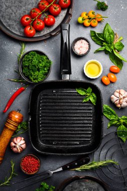 Aşçılık geçmişi. Izgara tavası ve sebzeli baharatlar gri beton bir masaya serilmiş. Üst Manzara. Metin için boş alan.