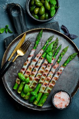 Taş tabakta domuz pastırmalı kızarmış kuşkonmaz. Üst görünüm.