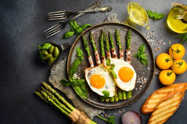 Kahvaltı: yeşil kuşkonmaz, tavuk yumurtası ve pastırma. Taş bir levhada, yakın plan..