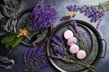 Lavanta aromalı Fransız Makaronları ve taze lavanta çiçekleri, taş bir tabakta. Üst görünüm.