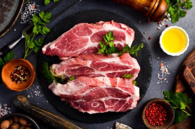 Tabakta baharatlı üç çiğ domuz bifteği. Çiğ et. Gri taştan bir arka planda.