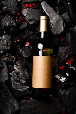 Kömürün arka planında şişe içinde beyaz şarap. Metin için boş alan. Üst görünüm.