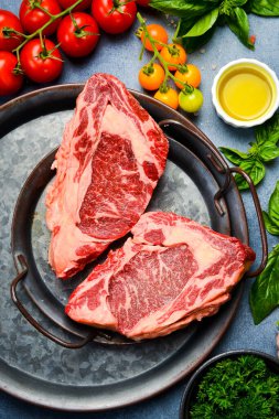 Çiğ Mermer Biftek. Gri taş bir masada biftek, baharat, baharat, tereyağı ve tuz pişirmek..