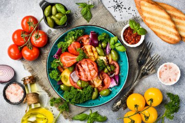 Taze domates salatası: domates, soğan ve zeytin. Gri beton arka planda.