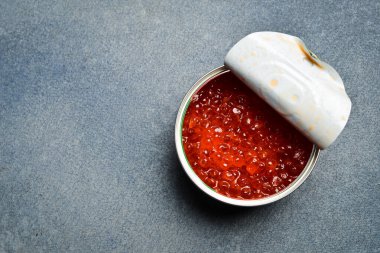 Bir kavanoz kırmızı somon havyarı. Ürünler Omega-3 açısından zengindir. Lezzetli deniz ürünleri atıştırmalıkları. Gri beton arka planda.