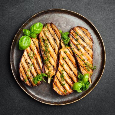 Bir tabak ızgara patlıcan. Izgara sebze. Üst Manzara. Gri beton arka planda.