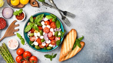 Bir kasede renkli salata: domates, mozzarella peyniri, fesleğen ve zeytin. Üst görünüm.