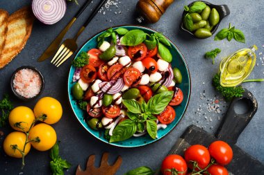 Taze yaz salatası: domates, mozzarella peyniri, fesleğen ve zeytin. Caprese. Gri beton arka planda.
