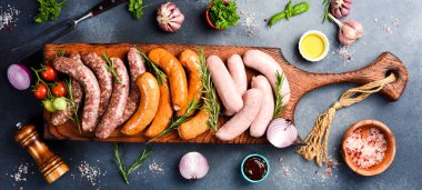 Büyük boy barbekü sosisi: sığır eti, domuz eti ve tavuk sosisi. Tahta kesme tahtasının üzerinde. Üst görünüm.