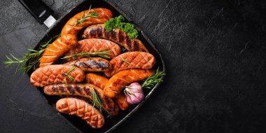 Domuz eti, sığır eti ve tavuk sosisi ile ızgara. Üst Manzara, kapat. Siyah taştan bir arka planda.