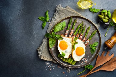 Kahvaltı: yeşil kuşkonmaz, tavuk yumurtası ve pastırma. Taş bir levhada, yakın plan..