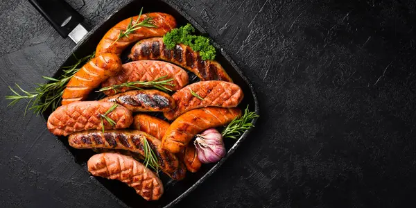 Domuz eti, sığır eti ve tavuk sosisi ile ızgara. Üst Manzara, kapat. Siyah taştan bir arka planda.