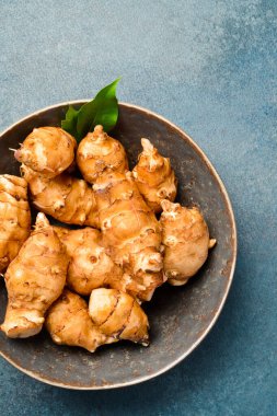 Seramik kasede organik çiğ Kudüs enginar kökü. Gri taştan bir arka planda. Yakın plan. Metin için boş alan.