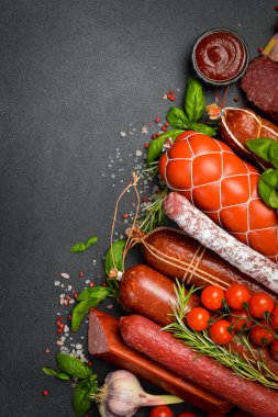Dikey görüntü. Siyah monokrom masasında sosis ve salam. Üst Manzara. Metin veya tasarım için boş alan. Et ürünleri.