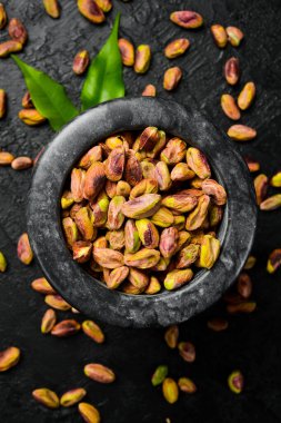 Fıstık taneli taş havan topu, fıstıklı un. Makro fotoğraf, yakın plan, siyah bir tahta üzerinde..