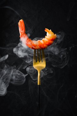 Çatalda ızgara karides. Siyah taşlı arka planda deniz ürünleri.