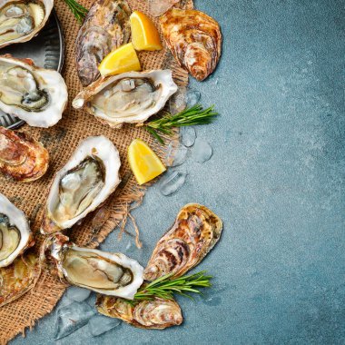 Limonlu ve buzlu taze istiridye, yemeye hazır, gri taştan bir arka planda..