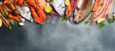 Taze deniz ürünleri. Geniş çeşitlilikte balık, karides, ıstakoz, ahtapot ve diğer deniz canlıları. Gri desenli taş arka planda. Metin veya tasarım için boş alan.