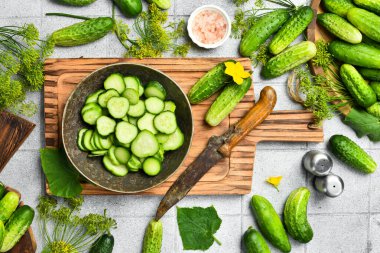 Taze yeşil salatalık dilimleri seramik kasede yiyecek stili için. Taş bir masa arkasında. Üst görünüm.