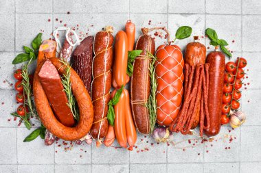 Farklı türde tütsülenmiş salam ve sosis. Gri taştan bir arka planda. Üst Manzara. Metin için boş alan.