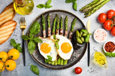 Faydalı bir kahvaltı. Kızarmış kuşkonmaz, pastırma ve kızarmış yumurta tabağı. Üst görünüm.