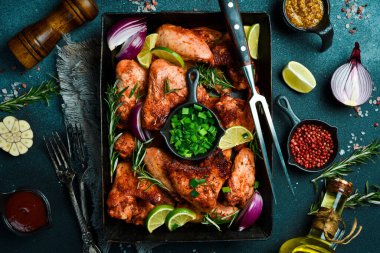 Izgara menüsü, barbekü. Metal bir tepside fırında tavuk kanadı. Karanlık bir arka planda.