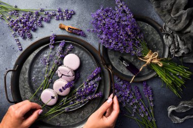 Mor badem kurabiyeleri ve kadın ellerinde bir demet lavanta. Üst Manzara. Metin için boş alan.