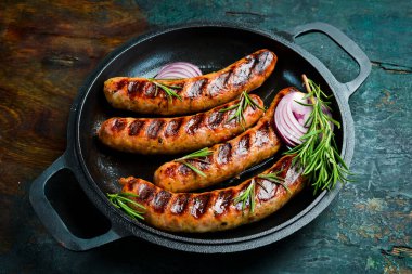 Izgarada, tavada pişmiş sulu sığır eti sosisi. Kapatın. Üst görünüm.