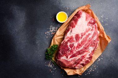 Parşömen kağıdının üzerinde pişmeye hazır bir parça domuz eti. Çiğ et. Gri taştan bir arka planda.