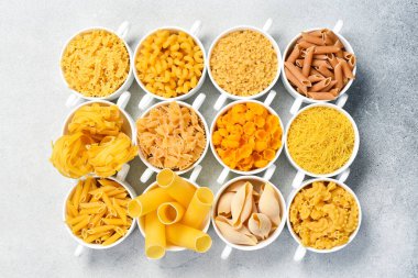 Aydınlık taş masada farklı pişmemiş makarna. Üst görünüm.