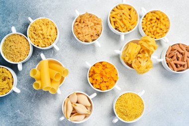 Aydınlık taş masada farklı pişmemiş makarna. Üst görünüm.