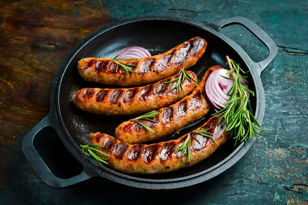 Izgarada, tavada pişmiş sulu sığır eti sosisi. Kapatın. Üst görünüm.