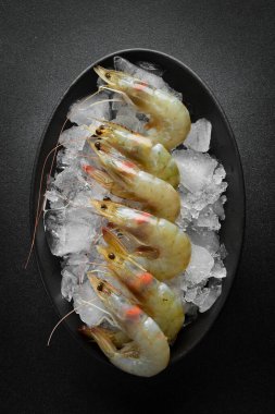 Buzlukta limonlu çiğ karides. Koyu dokulu bir arkaplanda.