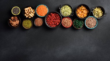 Superfood ve tahıl seçimleri kase içinde: chia tohumu, bezelye, yeşil spirulina, goji üzümü ve fındık, kuru üzüm, karabuğday, keten ve kinoa. Metin için boş alan.