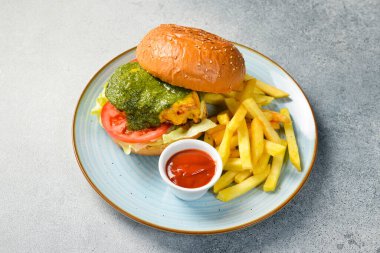 Patates ve peynirli geleneksel bir burger, patates kızartması ile servis edilir. Taş bir masada. Kapat..