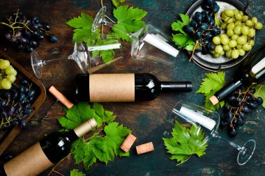 Taş bir masanın üzerinde şarap şişeleri, bardaklar, üzümler ve üzüm yapraklarının bileşimi. Üst Manzara. Metin için boş alan.