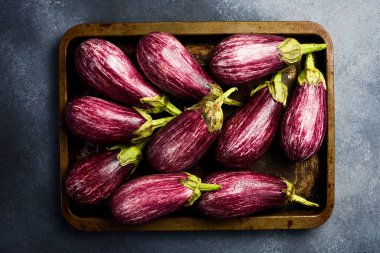 Bir avuç patlıcan ve metal tepside yeşil yapraklar. Organik sebzeler.