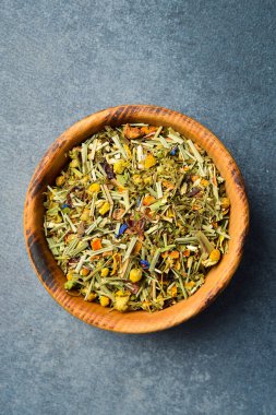 Tahta bir kasede kurutulmuş sağlıklı bitki çayı. Taş zeminde. Yakın plan..