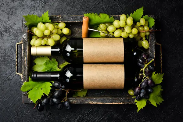 Bir şişe şarap, bir demet üzüm, bardak, tirbuşon ve tahta bir kutuda mantar. Üst görünüm.
