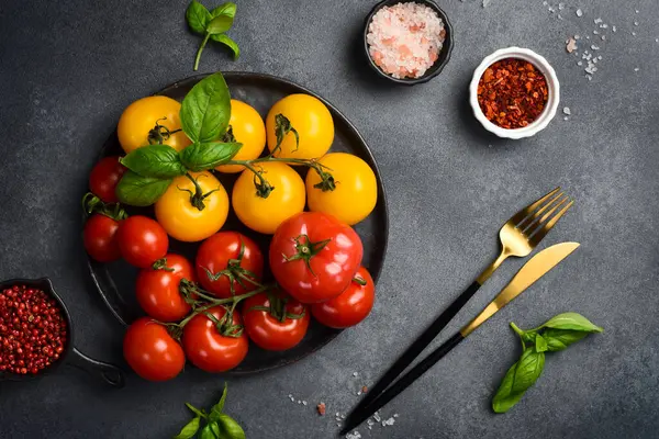 Siyah taş tabakta taze organik domatesler. Üst görünüm.