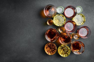 Sert alkollü içeceklerle dolu bir bardak seti: viski, brendi, konyak veya burbon ve rom. Üst Manzara. Güçlü alkollü içecekler. Siyah taştan bir arka planda.