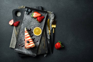 Çilek soslu ve yabanmersinli cheesecake. Tatlı. Karanlık bir arkaplanda, yakın plan.